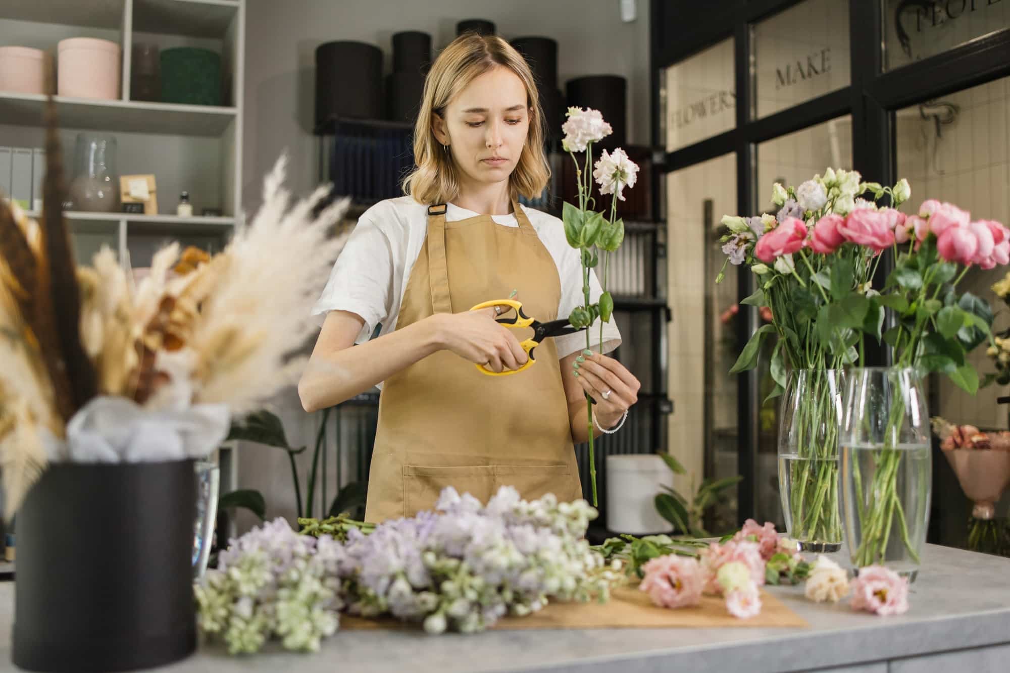 Cute girl florist collects a bouquet of roses in a flower shop.